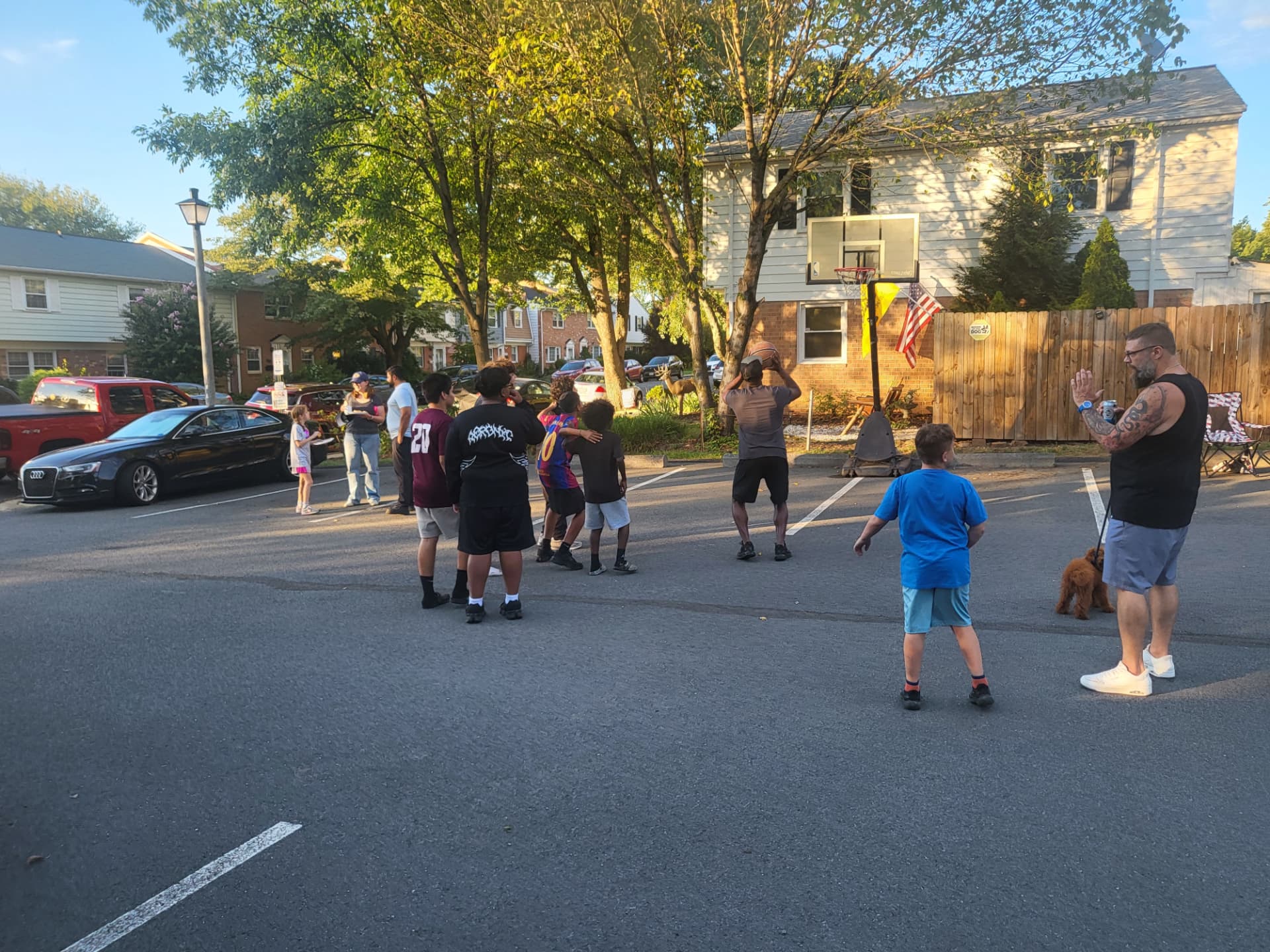 Kids and neighbors gathered around a basketball game in the parking lot