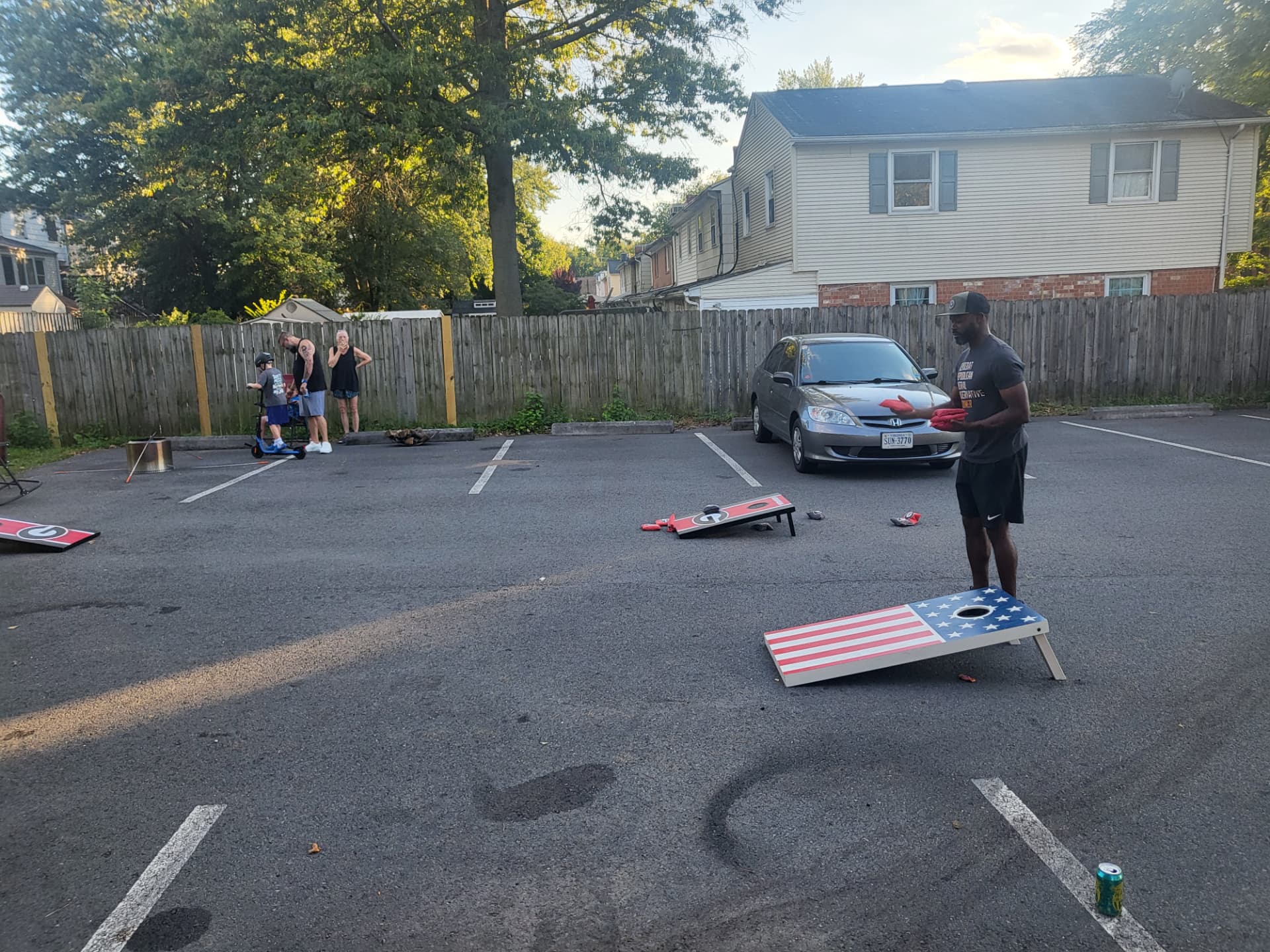 Neighbors playing cornhole in the parking lot during the Labor Day cookout